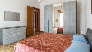 A bedroom with a bed, a dresser, a wardrobe, and a mirror.