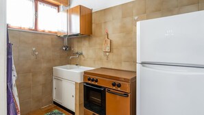 A kitchen with a white refrigerator, a stove, a sink, and a window with curtains.