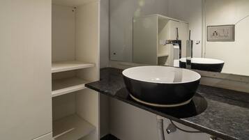 Un baño moderno con tocador blanco, lavamanos negro y espejo.