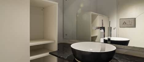 A modern bathroom with a white vanity, a black sink, and a mirror.