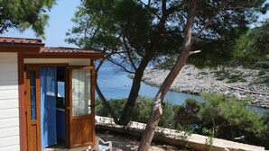 A wooden cabin with a glass door, a small porch, and a view of the sea.