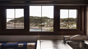 A kitchen with a large window overlooking a coastal landscape.