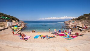 Une plage où l’on peut se détendre au soleil et se baigner, avec une eau d’un bleu limpide et une côte rocheuse.