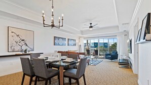 A spacious living room with a dining area, large windows, and a ceiling fan.