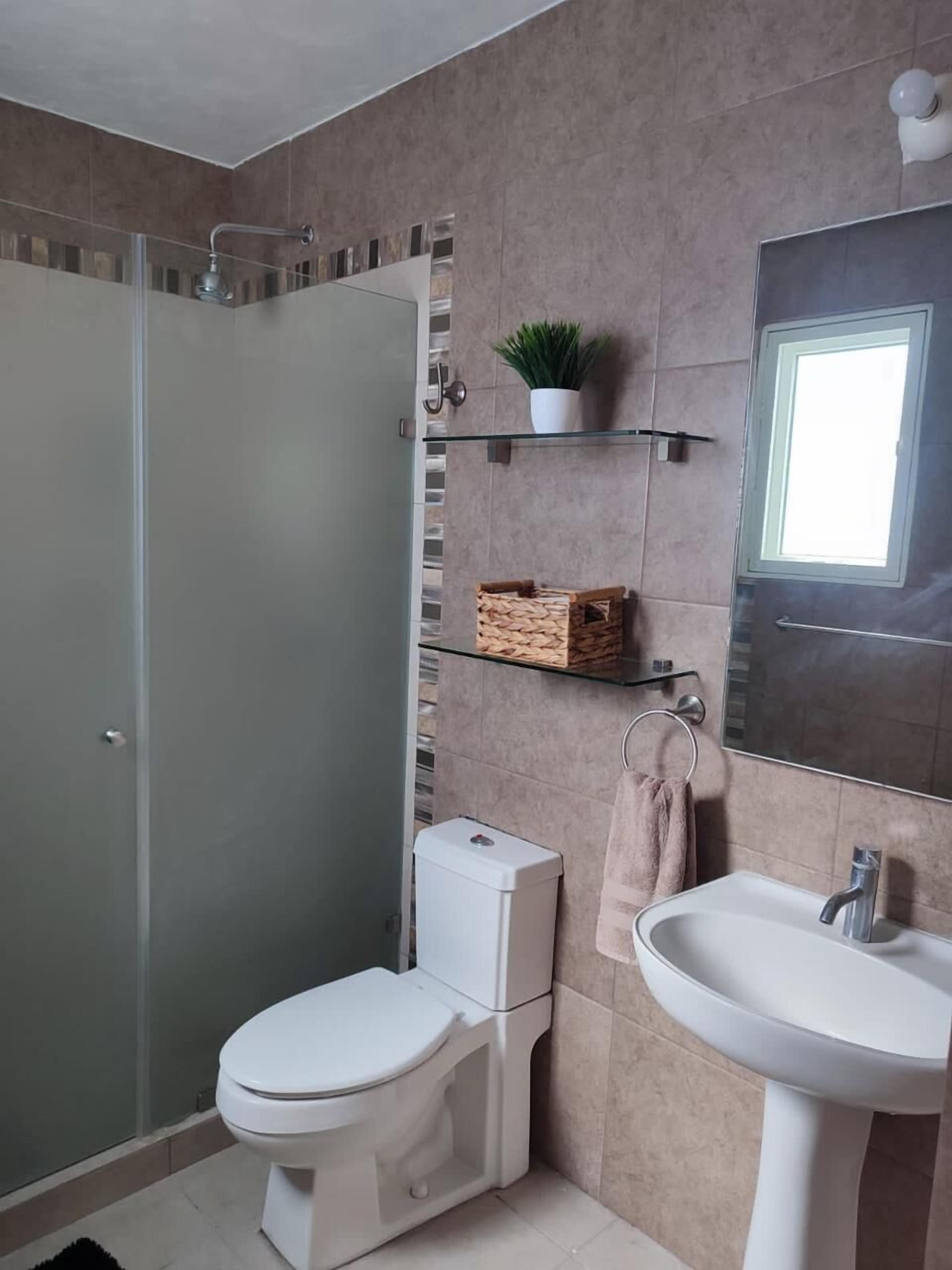 Une salle de bain moderne avec une douche à parois de verre, des toilettes, un lavabo et un miroir.