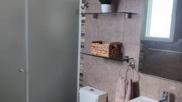 Une salle de bain moderne avec une douche à parois de verre, des toilettes, un lavabo et un miroir.