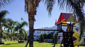 A playground with swings, a slide, and a climbing structure. - CASA LAUREL (Corregidora)