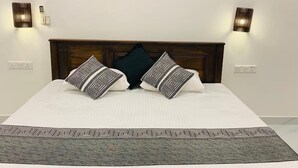 A bedroom with a wooden headboard, a bed with patterned bedding, and three wall-mounted paintings of a tree. - Ibeeza Motel (Batigama)