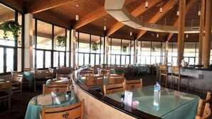 Un restaurante con vigas de madera, mesas de vidrio y sillas.