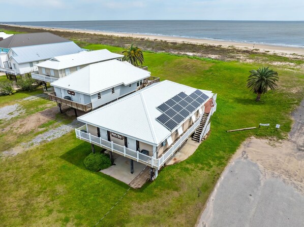 A beachfront property with a large house featuring a balcony and solar panels. - Milky Way Beach Front: Coastal Realty Group (Grand Isle)