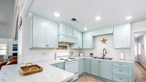 A kitchen with light blue cabinets, a white marble countertop, and a star decoration on the wall. - Milky Way Beach Front: Coastal Realty Group (Grand Isle)