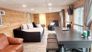 Ein gemütliches Zimmer mit einem Bett, einem Ledersofa, einem Esstisch mit Stühlen und einem an der Wand befestigten Fernseher.