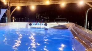 Ein Whirlpool unter einem Holzdach mit Stadtansicht im Hintergrund.