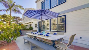 An outdoor patio with a table set for dining, a bench, and a striped umbrella. - Fantastic Bayside Vacation Home w/ WiFi, Private Washer/Dryer, Central AC, Patio (San Diego)