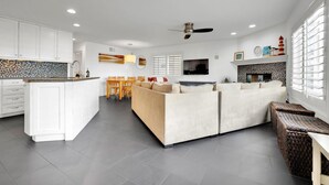 A modern kitchen with white cabinets, a central island, and a dining area with a sofa and chairs. - Fantastic Bayside Vacation Home w/ WiFi, Private Washer/Dryer, Central AC, Patio (San Diego)