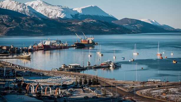 A harbor with boats, a large ship, and mountains in the background. - Moat Apartamento (Ushuaia)