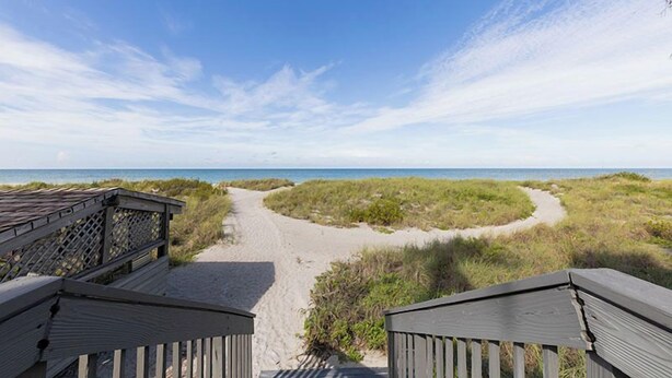 A wooden boardwalk leading to a beach with dunes and a clear sky. - Tiffany Plaza in Longboat Key, FL (Longboat Key)