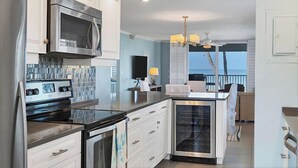 A modern kitchen with stainless steel appliances, white cabinetry, and a large island. - Tiffany Plaza in Longboat Key, FL (Longboat Key)