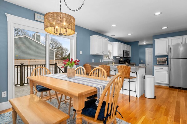 A modern kitchen with white cabinets, stainless steel appliances, and a dining area with a wooden table and chairs.