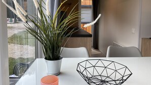 A modern dining area with a white table, a metal geometric bowl, and a potted plant with white flowers. - Tiny Haus Sonnenplatz by Interhome (Riedenburg)