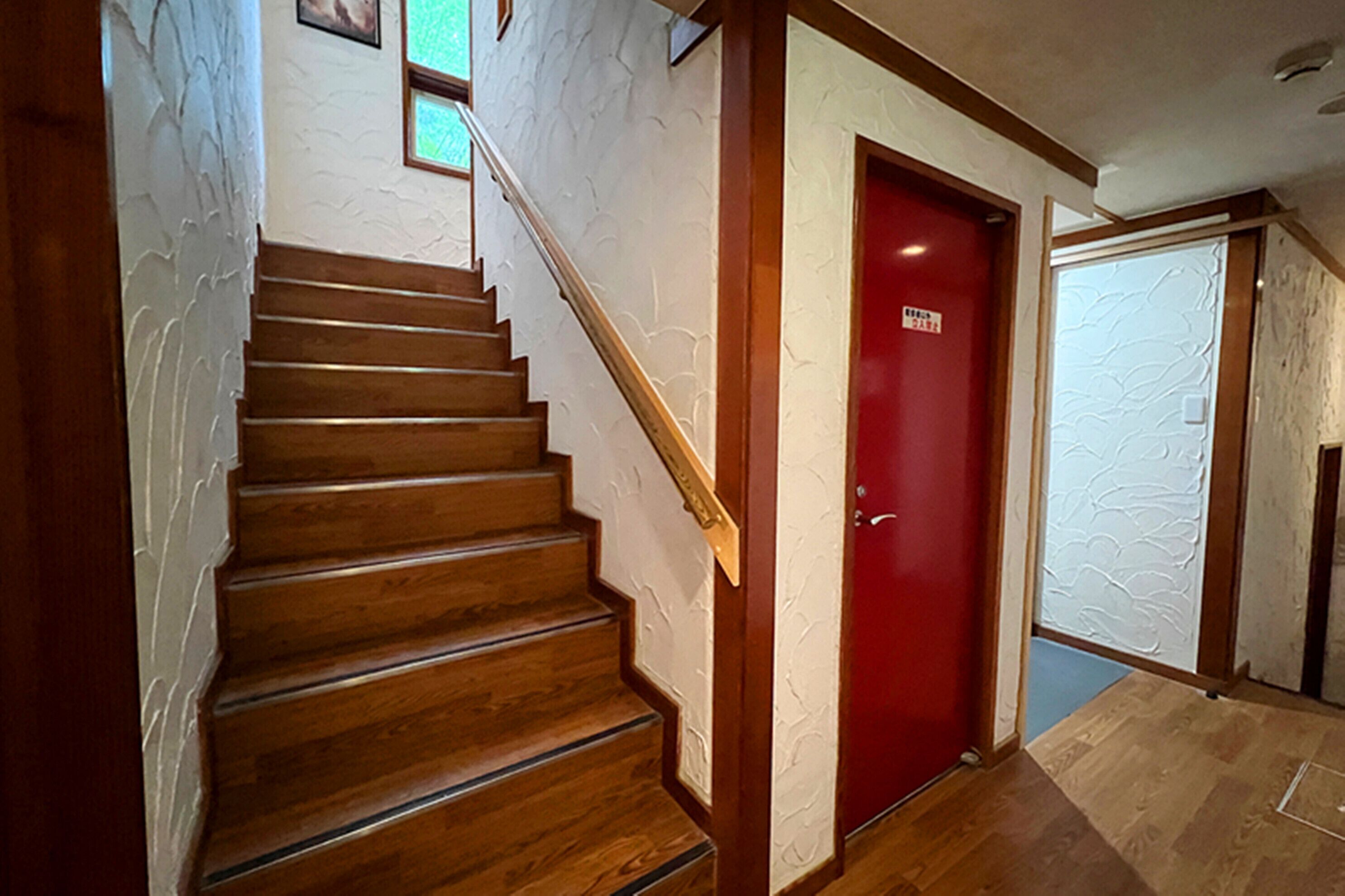 A wooden staircase with a red door at the top.