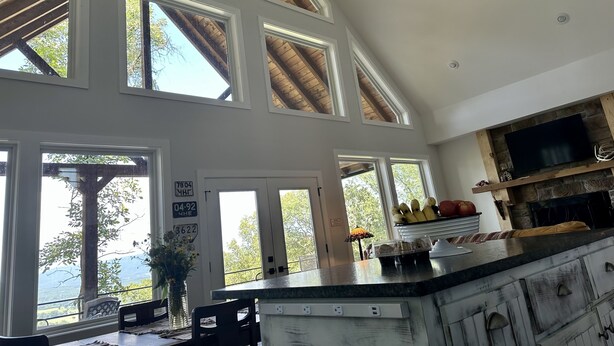A spacious kitchen with high ceilings, large windows, and a stone fireplace. -  Secluded Chickalah Mt. retreat overlooking beautiful Harkey Valley! (Belleville)