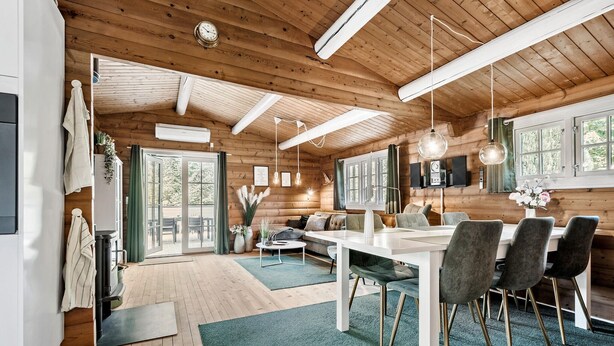 A cozy log cabin interior with a dining area, a sofa, and a fireplace.