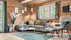 A cozy log cabin interior with a sofa, armchair, and a coffee table.