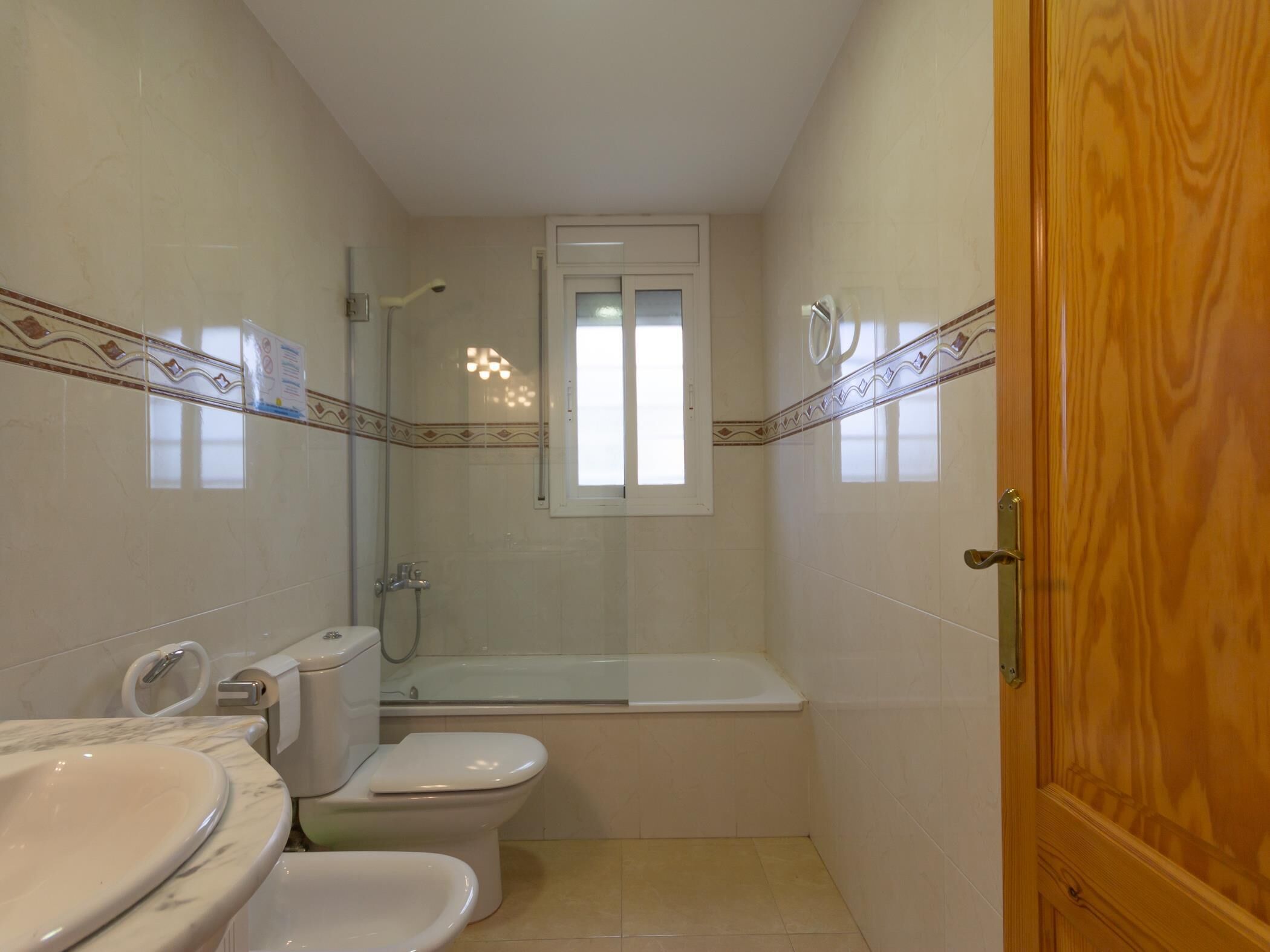 A compact bathroom with a toilet, bidet, and bathtub.