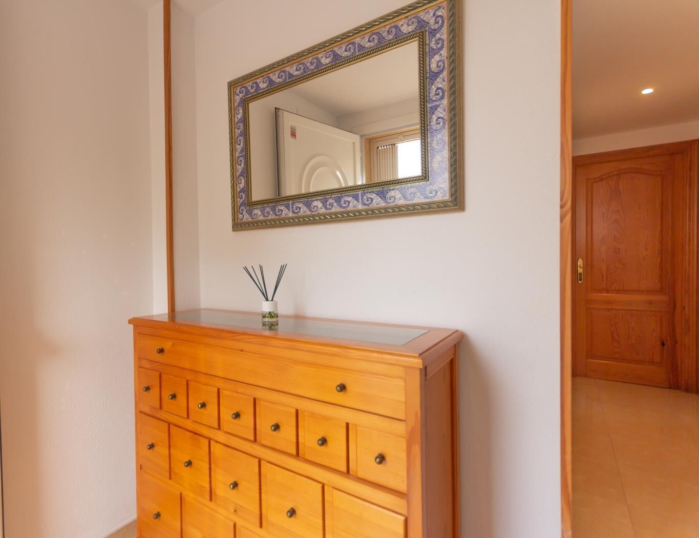 Un aparador de madera con varios cajones y un espejo con un marco decorativo.