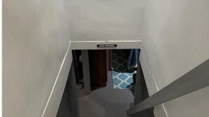 A narrow stairway with a handrail on one side and a tiled floor.