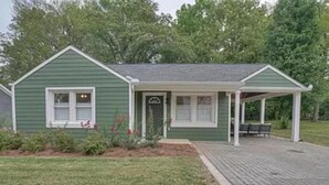 A green building with a porch, a small window, and a door.