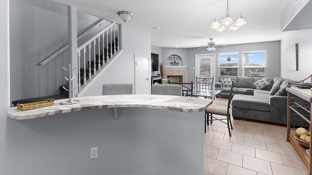 A modern kitchen with a marble island, grey walls, and a staircase.