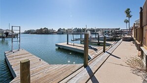 A wooden dock extending into calm water with a clear sky above.