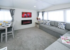 A modern living room with a flat-screen TV, a fireplace, a sofa, and a dining area. - 3 bedroom accommodation in Slaley, Hexham (Slaley, Hexham)