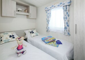 A bedroom with two beds, a wardrobe, a window with curtains, and a plush toy. - 3 bedroom accommodation in Slaley, Hexham (Slaley, Hexham)