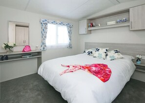 A bedroom with a bed, a vanity with a mirror, a window with curtains, a shelf with books, and a small vase with flowers. - 3 bedroom accommodation in Slaley, Hexham (Slaley, Hexham)