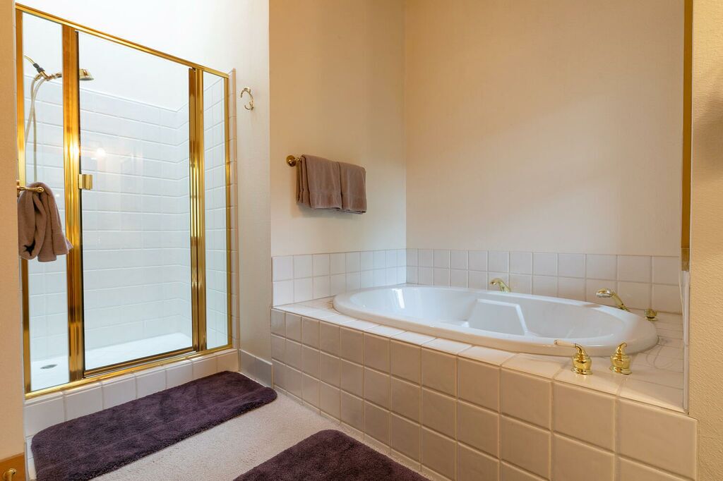 A bathroom with a glass shower enclosure, a bathtub, and a towel rack.