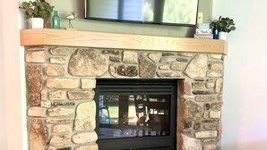 A stone fireplace with a flat-screen TV mounted above it. - Fish Creek, Door County Condo - Walk to Shopping, Dining & Peninsula State Park (Fish Creek)