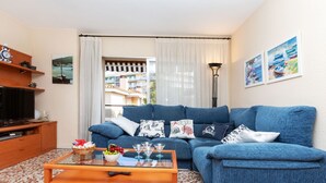 A living room with a blue sofa, a wooden coffee table, and a television on a wooden cabinet. - Venecia by Interhome (Playa de Aro)