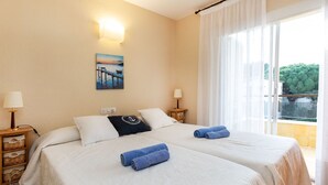 A hotel room with two beds, a painting on the wall, and a view of greenery outside. - Venecia by Interhome (Playa de Aro)