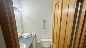 A small bathroom with a toilet, sink, and a wooden door. - Country Cabin Motel (Quincy)