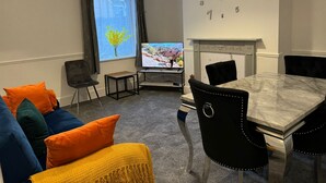 Moderni olohuone, jossa on sohva, pieni pöytä, televisio ja takka.