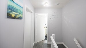 Un pasillo con un cuadro de una playa, una puerta y una pared que dice 'HOME LOVE'.