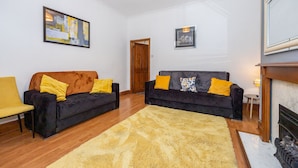 Una sala de estar con dos sofás, un tapete amarillo y una chimenea.