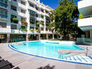 Un hôtel moderne doté d’une piscine centrale, d’un espace extérieur aménagé et de balcons agrémentés de plantes.