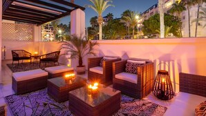 An outdoor seating area with wicker furniture and a decorative lantern. - Banús, Playas del Duque, Beachfront Residential! (Puerto Banús)