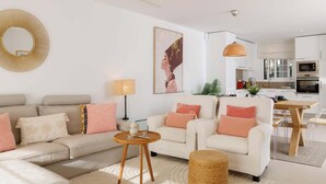 A modern living room with a sofa, armchairs, a coffee table, and a dining area.