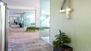 A modern hallway with glass walls, potted plants, and a geometric light fixture. - Jardines del Príncipe Golden Mile Suite Apartment (Marbella Golden Mile)