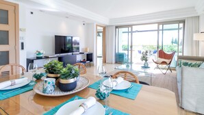 A modern dining area with a wooden table set for four, a television, and a balcony with outdoor seating. - Jardines del Príncipe Golden Mile Suite Apartment (Marbella Golden Mile)